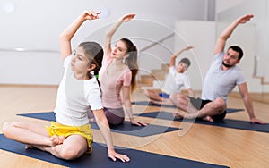 Girl practicing yoga at studio with family