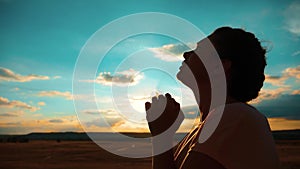 Girl praying. Girl folded her hands in prayer silhouette at sunset. slow motion video. Girl folded her hands in prayer