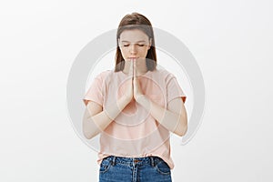 Girl praying for health and peace. Portrait of focused relaxed good-looking woman with short hair, closing eyes, holding