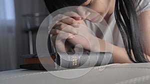 Girl praying indoors at bedtime on bible. religion concept evening prayer believer woman brunette hands on bible praying