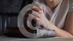 Girl praying indoors at bedtime on bible. religion concept evening prayer woman brunette hands on bible lifestyle