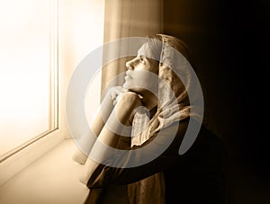 Girl praying by the window