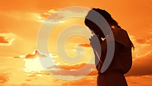 The girl prays. Girl folded her hands in prayer silhouette at sunset. slow motion video. Girl folded her hands in prayer