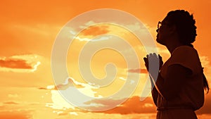 The girl prays. Girl folded her hands in prayer silhouette at sunset. slow motion video. Girl folded her hands in prayer