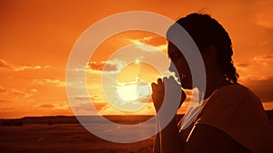 The girl prays. Girl folded her hands in prayer silhouette at sunset. slow motion video lifestyle. Girl folded her hands