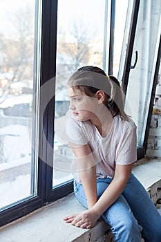 Girl of pre-teen age  sad near   window