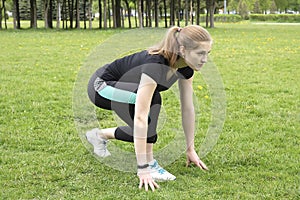 The girl in the prelaunch position before the run. Fitness in the park in front of the house photo