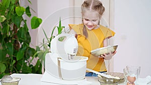 The girl prepares dough or cream in a submersible mixer, adds cottage cheese.