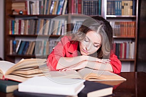 Girl is preparing for the exam in the library reads books