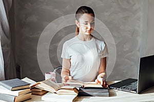 Girl is preparing for the exam reading book works at the computer