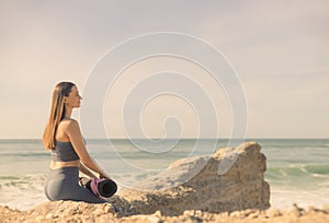 A girl is preparing to practice outdoor yoga on the ocean. Calmness and relax. Background with ocean view and yoga