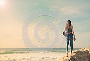 A girl is preparing to practice outdoor yoga on the ocean. Calmness and relax. Background with ocean view and yoga