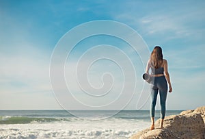 A girl is preparing to practice outdoor yoga on the ocean. Calmness and relax. Background with ocean view and yoga