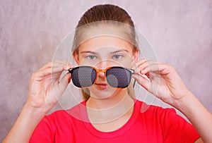 The girl is preparing to try on training glasses for vision correction