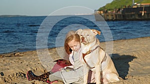 Girl preschool girl on the beach feeds the dog. Spring