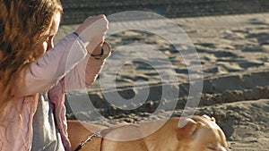 Girl preschool girl on the beach feeds the dog. Spring