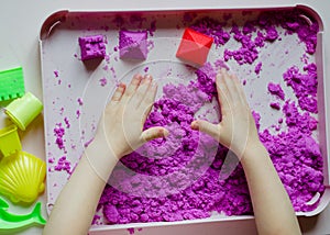 Kid`s hands with kinesthetic sand photo