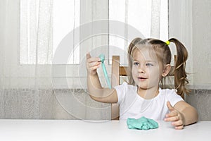 Girl preschooler sits at a table and sculpts from turquoise dough for modeling. activities with children at home on self-isolation