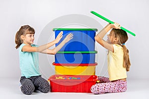 A girl pretending to be a hundred wants to throw a toy box lid on another girl