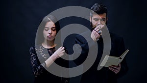 Girl and priest dressed in black baptized on a black background. Priest prays on a black background. Religious nun in