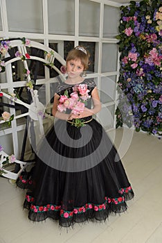 Girl princess in a black dress with a becket of flowers in her hands