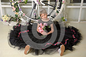 Girl princess in a black dress with a becket of flowers in her hands