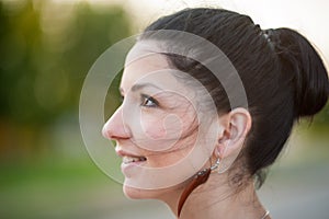 The girl in profile is smiling, close-up. Profile side portrait of a beautiful young happy smiling woman