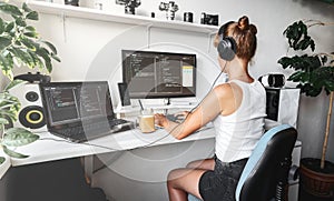 Girl programmer in the modern developer workplace for writing code with white computer desktop and comfy armchair.