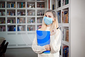 Girl in a protective face mask at the university library. Coronavirus infection concept.