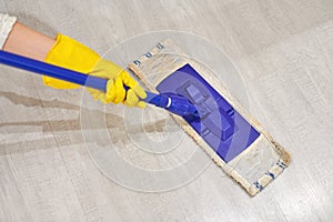 Girl in protective gloves cleaning floor using flat wet mop