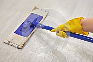 Girl in protective gloves cleaning floor using flat wet mop