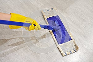 Girl in protective gloves cleaning floor using flat wet mop