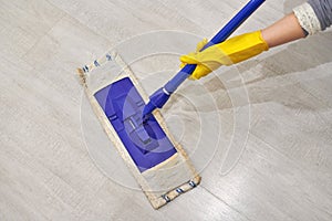 Girl in protective gloves cleaning floor using flat wet mop