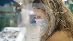 Girl in protective mask carefully selects products in supermarket, quarantine coronovirus security measures