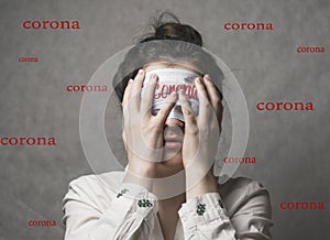 A girl in a protective mask covers her face with her hands and does not want to hear more about coronavirus