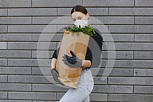 Girl in protective mask holds package with products