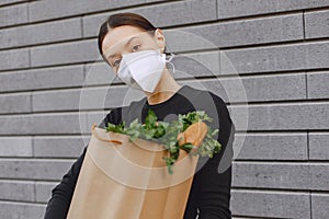 Girl in protective mask holds package with products