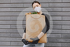 Girl in protective mask holds package with products