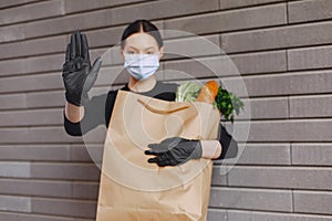 Girl in protective mask holds package with products