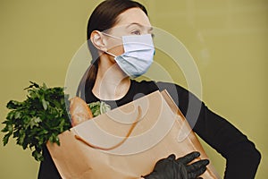 Girl in protective mask holds package with products