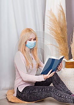 Girl in protective medical mask reads a book.