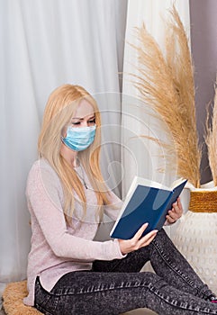 Girl in protective medical mask reads a book.