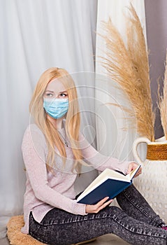 Girl in protective medical mask reads a book.