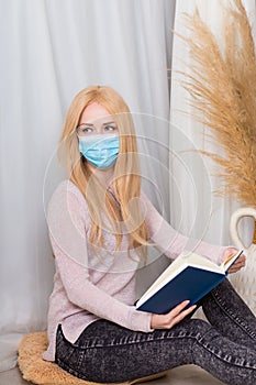 Girl in protective medical mask reads a book.