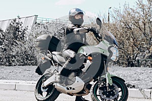 A girl in a protective suit and a black helmet sits on a sports motorcycle.