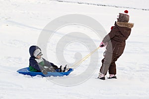 Girl pulling boy children kids toboggan sled snow
