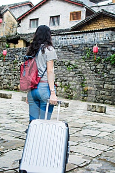 Girl pulling the suitcase walking in the ancient town