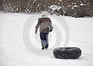Girl pulling tube up sledding hill photo