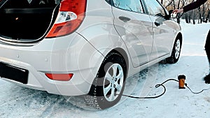 A girl is pumping up a flat tyre in winter