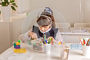 A girl pupil disassembles a box with small toys motor skills development. ncept